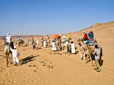 一辆旅行车的游客在穿越努比亚沙漠骆驼