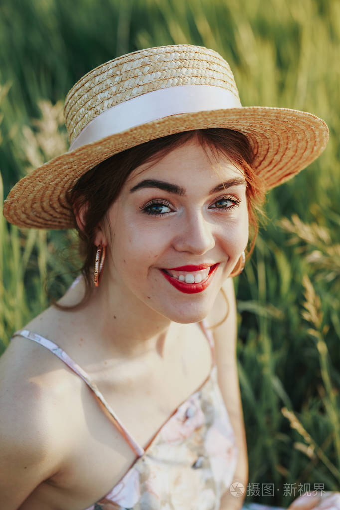 一个戴草帽的女孩的肖像看着相机微笑着