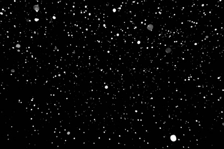 在黑色背景上的散景灯拍摄的飞片雪花在空中照片