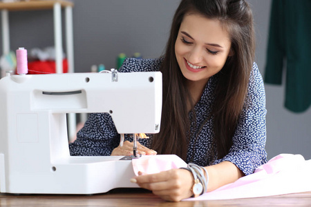 在画室里使用缝纫机的年轻女性裁缝