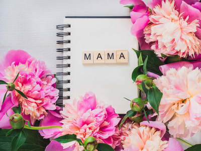 空白页的笔记本与字妈妈的问候题词在开花的背景。顶部视图, 特写, 隔离。恭喜亲戚们。幸福家庭的概念
