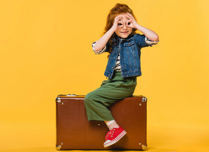 坐在手提箱的孩子的侧面看黄色照片