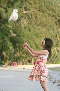 亚洲女孩玩弄她的帽子在海滩旁边