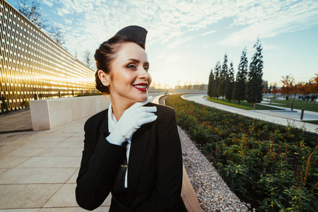 穿着制服的年轻女空姐在公园里等待她的飞行