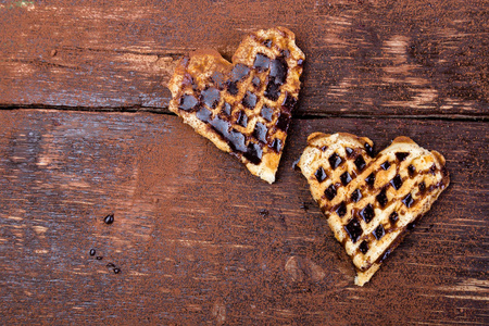 两个比利时心脏形状的华夫饼与巧克力在木背景。平躺。复制空间