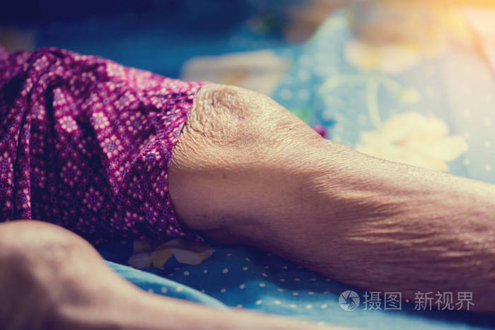 老太婆的膝盖和腿睡在床上.老太婆皮肤的皱纹