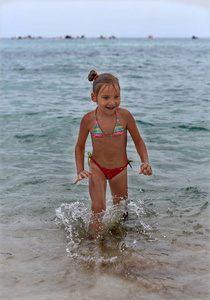 笑的小女孩站在大海的波涛