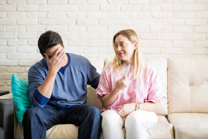 年轻男子感到担心后, 知道怀孕测试结果从他的女朋友坐在沙发上在家