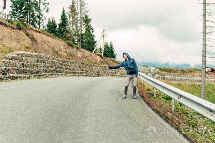 男人男孩旅行者捉住汽车在路搭便车竖起大拇指