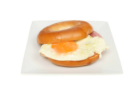 火腿和煎蛋在一个面包圈上的盘子查出的白色
