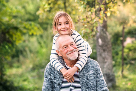 祖父背着他的 grandaughter 在他的肩膀上