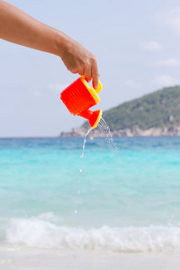 女性的手从孩子的塑料浇灌罐头倾吐水。安达曼海, 斯米兰群岛