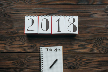 2018年日历和笔记本的顶部视图, 在木制桌面上做刻字