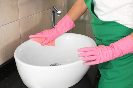 妇女在保护手套清洁浴室水槽与抹布, 特写镜头