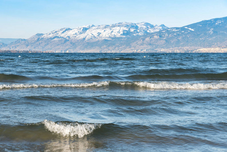 海浪坠落在海岸线上, 积雪覆盖的山脉和蓝天