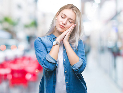 年轻的金发女人在孤立的背景下睡觉疲倦的梦想和手一起摆姿势, 而微笑着闭着眼睛