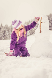 小女孩在森林里建造雪人