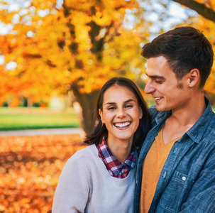在秋天笑户外公园对年轻夫妇的肖像