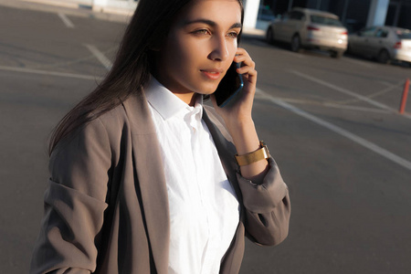 年轻迷人的女孩在商务西装使用智能手机。生活方式和商业肖像