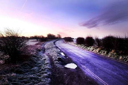 一个乡间小路, 右边是一条曲线, 道路上和乡村的霜, 红色的黎明在天空中升起