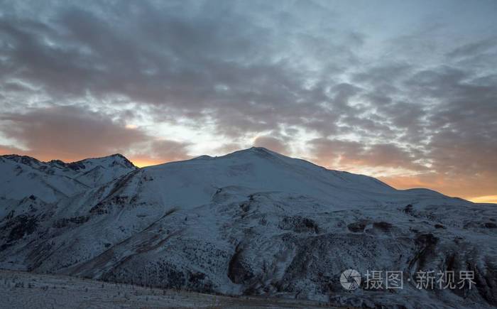 冬季的衰落超过雪山, 美丽的色彩在多云的天空, 日落, 北高加索的性质