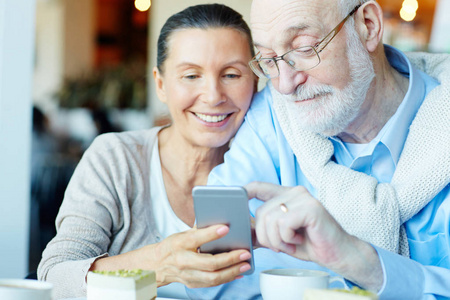 高级夫妇与智能手机短信在咖啡馆