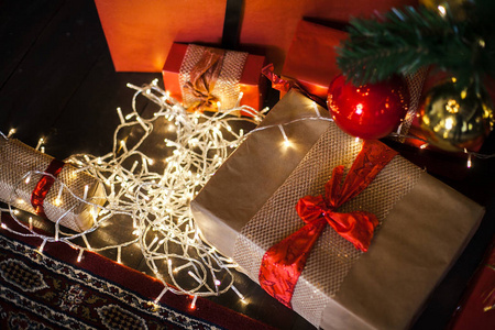 圣诞节礼物包裹在棕色和红色的纸在阁楼, 背景与圣诞灯模糊的圣诞树的散景。复制空间