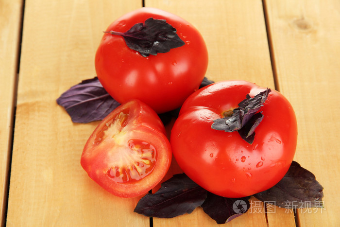 新鲜番茄和罗勒叶木制背景上
