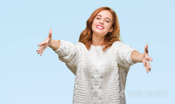 美丽的女人在与世隔绝的背景穿着冬季毛衣看着相机微笑着张开双臂拥抱