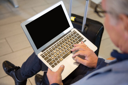 在机场大厅中使用的笔记本电脑的商人的特写