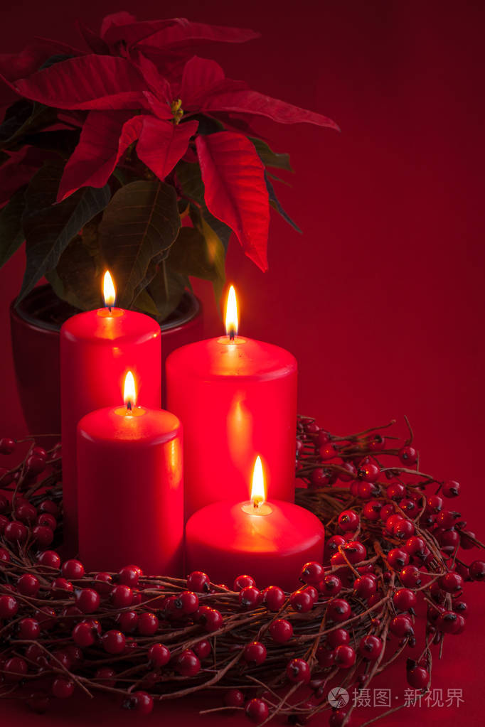 红色燃烧出现圣诞蜡烛与浆果花圈和一品红在红色背景.调子