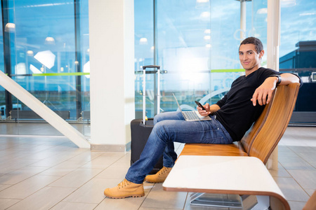 移动电话和笔记本电脑在机场的年轻人