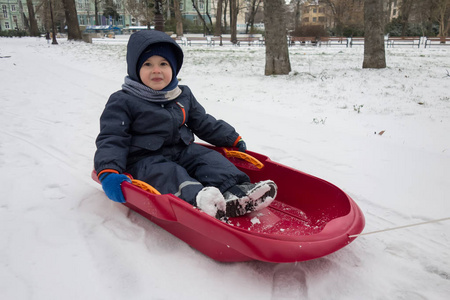 快乐的小男孩，在他的雪橇在冬天的雪