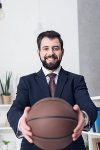 微笑的生意人的选择的焦点显示篮球在办公室手