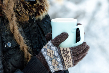 在手套捧着杯茶，白色雪背景的女孩