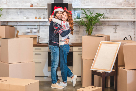快乐的年轻夫妇拥抱和微笑的相机, 而搬迁在新家在圣诞节
