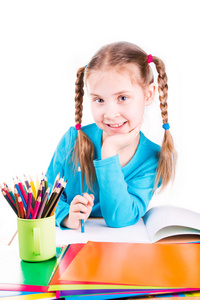 可爱微笑的小姑娘用彩色铅笔在磨炼中绘制一张图片