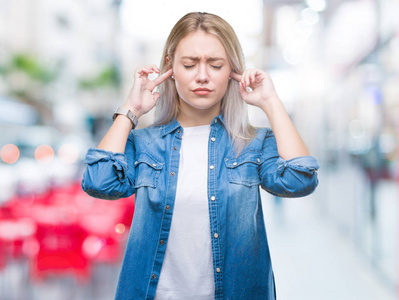 年轻的金发女人在孤立的背景覆盖耳朵与手指与愤怒的表达大声音乐的噪音。聋的概念