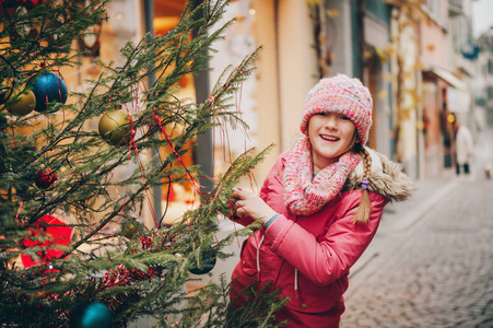 快乐的小女孩在旧欧洲城市的街道上玩圣诞树, 和孩子们一起度假, 在洛桑拍摄的照片瑞士
