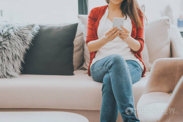 女性坐在沙发上使用现代智能手机的镜头.技术与交流生活方式概念