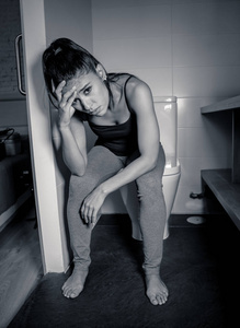 美丽的拉丁妇女坐在浴室患有厌食贪食感绝望悲伤和内疚在饮食失调和怀孕的概念