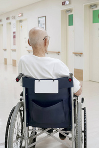老人坐在医院走廊轮椅上的后视图