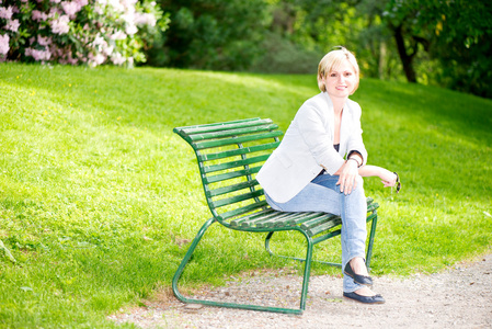 年轻女子坐在长凳上的公园和微笑