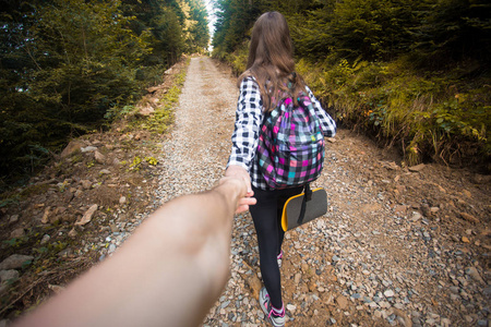 跟我来。年轻妇女的背部视图背包户外发现丛林持有男友手