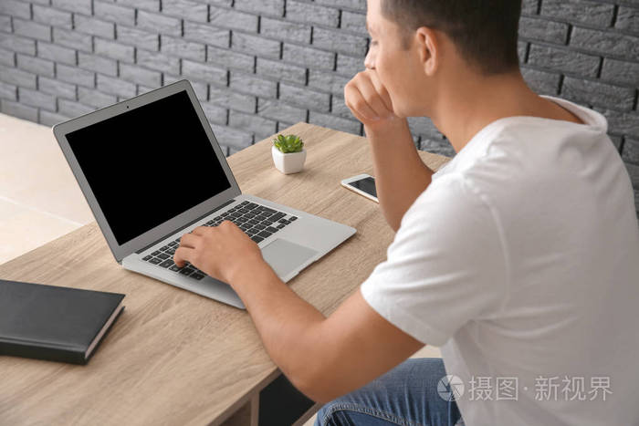 坐在桌子上的年轻人工作与笔记本电脑
