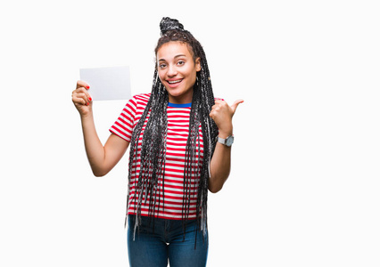 年轻的非洲裔美国女孩拿着空白卡在孤立的背景指向和显示与幸福的脸微笑的一侧