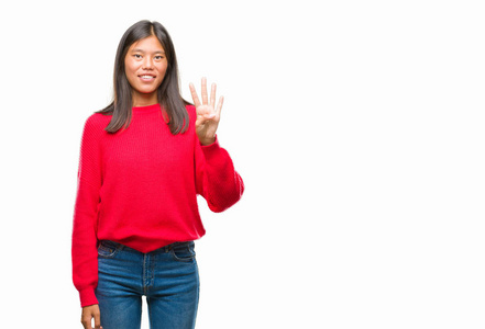 年轻的亚洲妇女穿着冬季毛衣在孤立的背景显示和指向手指四, 而微笑着自信和快乐