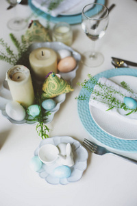 复活节和春天的节日餐桌, 用蓝色和白色的色调在自然质朴的风格, 与鸡蛋, 兔子, 鲜花和蜡烛