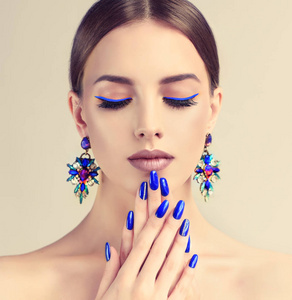 美丽的女人与时尚化妆和完美的蓝色指甲