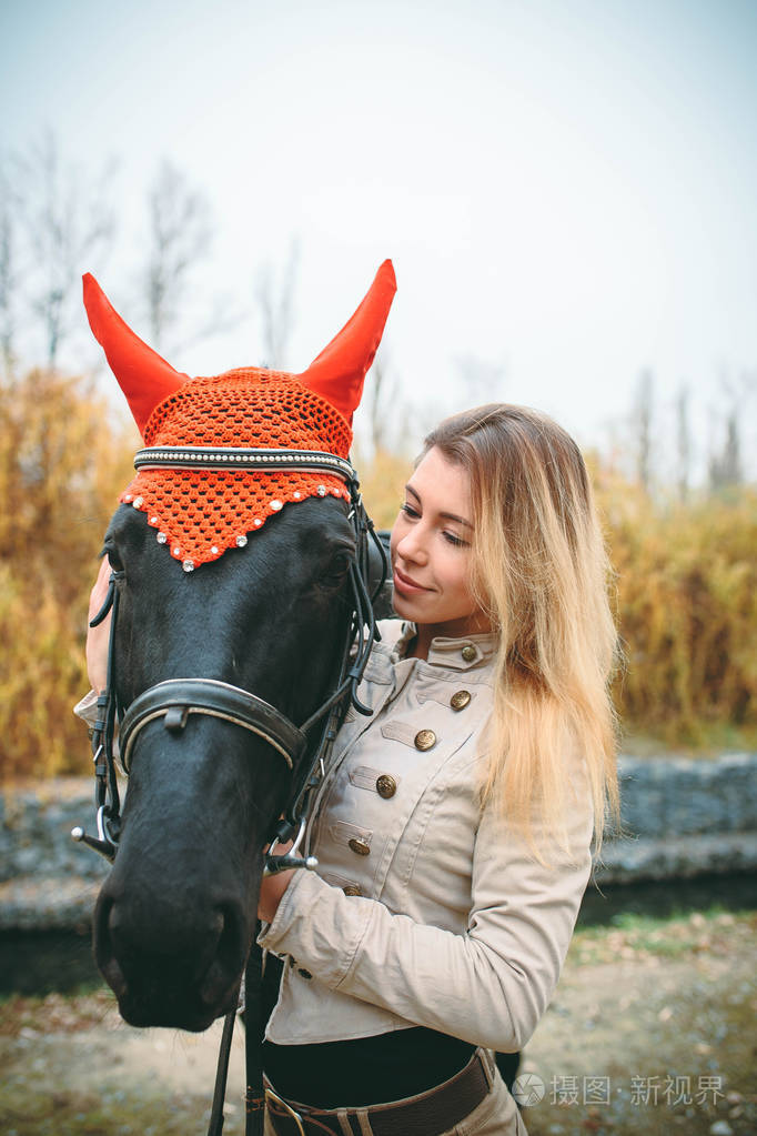 可爱的年轻金发女子在寒冷的秋天的一天马